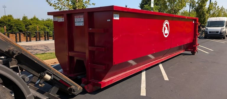 Red 30-yard Roll Off Operations dumpster being placed in a paved parking lot